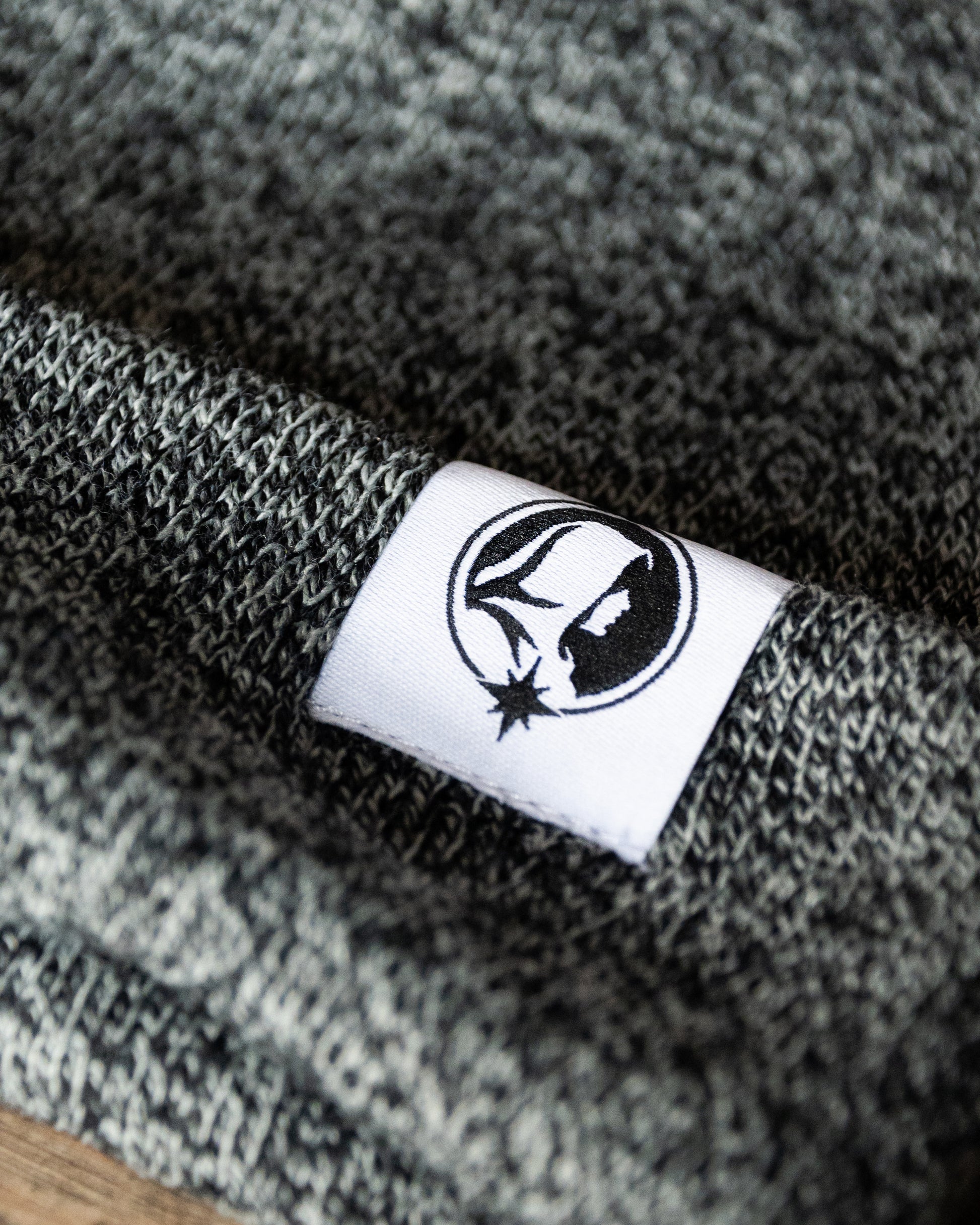 Close-up of a Northern Monk logo tab on a textured grey fabric.